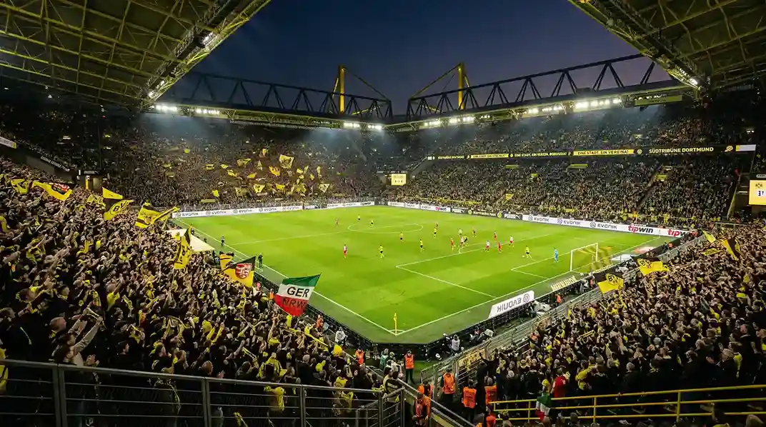 Blick auf ein volles Bundesliga-Stadion bei Flutlicht mit grünem Rasen
